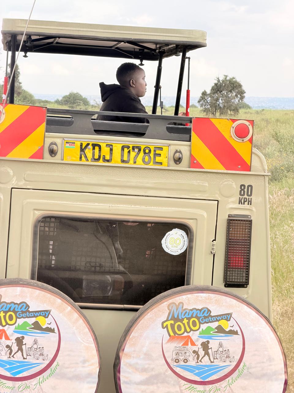 A young traveller looking out from the open roof of the Mama Toto safari vehicle
